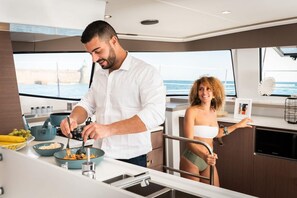 Une cuisine moderne avec vue sur la mer, un coin repas et une personne en train de cuisiner.