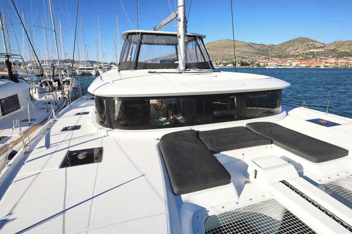 Un barco con camarote, zona de estar y vistas a un puerto deportivo y colinas.
