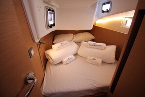 A compact cabin with a bed, pillows, and a small window. - Sun-Kissed Sailing Adventure in Zadar, Croatia (Biograd na moru)