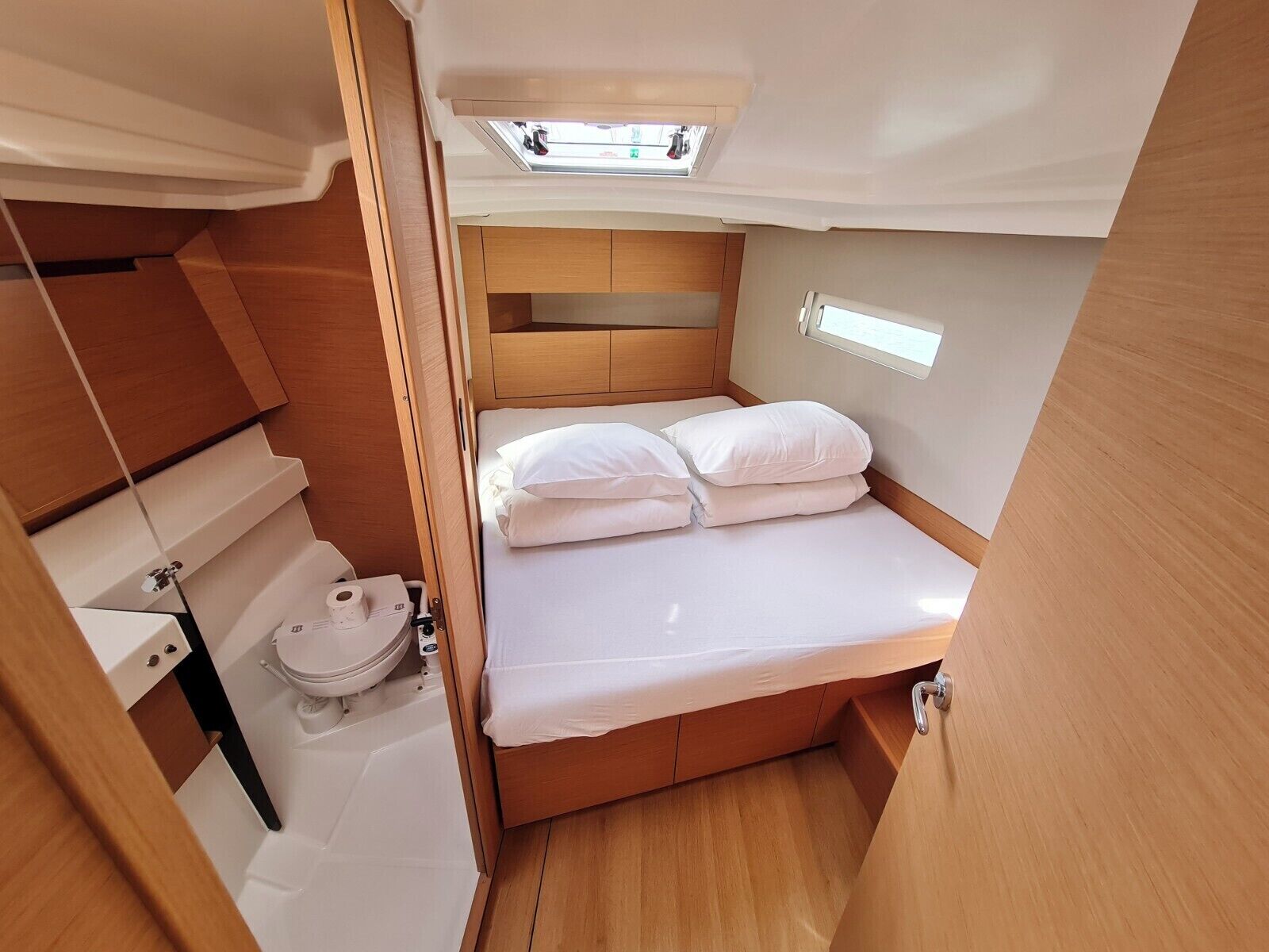 Ein gemütliches, helles Blockhaus mit Bett, Toilette und Dachfenster.