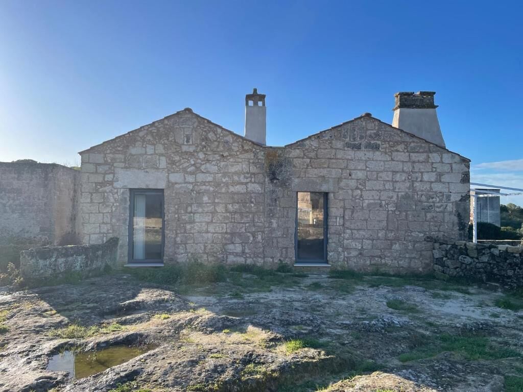 A stone building with two chimneys, a door, and a window.
