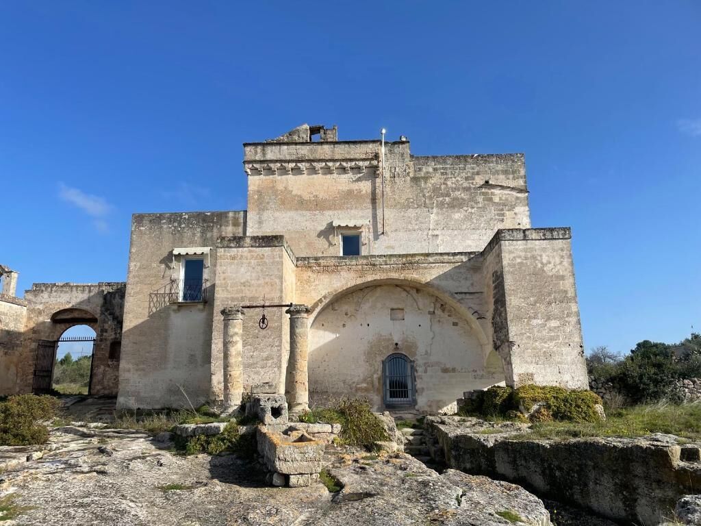An ancient stone building with arched doorways and a central entrance.