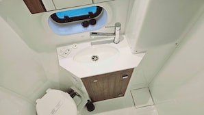 A bathroom with a white sink, a toilet, and a shower area.