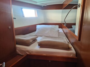 A compact cabin with a single bed, a small window, and a mirror.