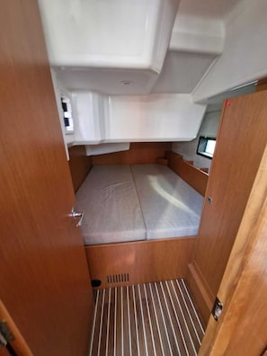 Ein kompakter Innenraum mit einem Bett, einem kleinen Fenster und einer Belüftungsanlage.