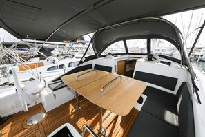 Een dek van een boot met een tafel, zitplaatsen en uitzicht op andere boten.