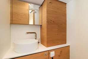 Een badkamer met een wit wastafel, houten kastjes en een spiegel.
