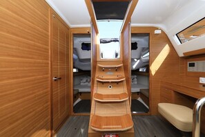 A compact interior with a central aisle, wooden cabinetry, a small seating area, and a control panel. - Sun-Kissed Sailing Adventure in Zadar, Croatia (Biograd na moru)