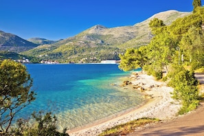 A coastal landscape with clear water, a sandy beach, and a mountainous backdrop. - Dubrovnik Delight: A Luxurious Sun and Beach Sailing Experience (Slano)