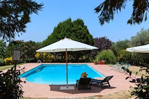 A swimming pool with lounge chairs and umbrellas, surrounded by greenery. - Double Room with Private Bathroom 1 (Stazzano)