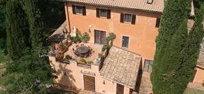 A building with a tiled roof, a courtyard with a round table and chairs, and a door labeled 'LOFT'.