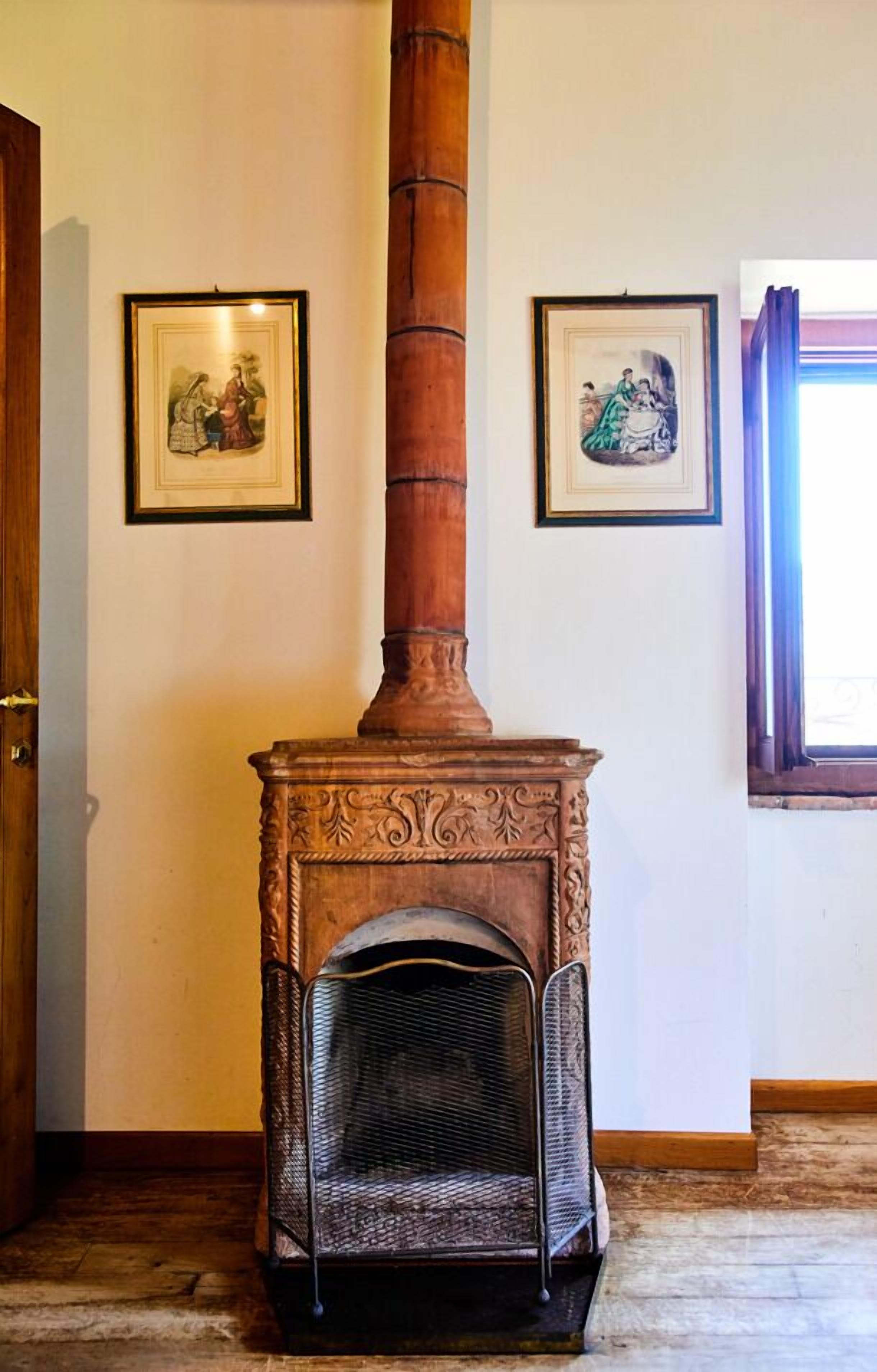 Ein Zimmer mit einem traditionellen Kamin, einer Tür und zwei gerahmten Bildern an der Wand.