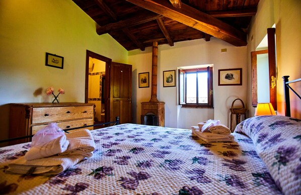 A bedroom with a bed, wooden dresser, and a fireplace.