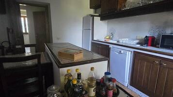 A kitchen with a central island, wooden cabinets, a refrigerator, and various kitchen items on the counter.