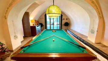 A pool table with a green felt surface, surrounded by a white wall with an arched doorway.