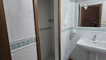 A bathroom with a shower, a sink, and a mirror.