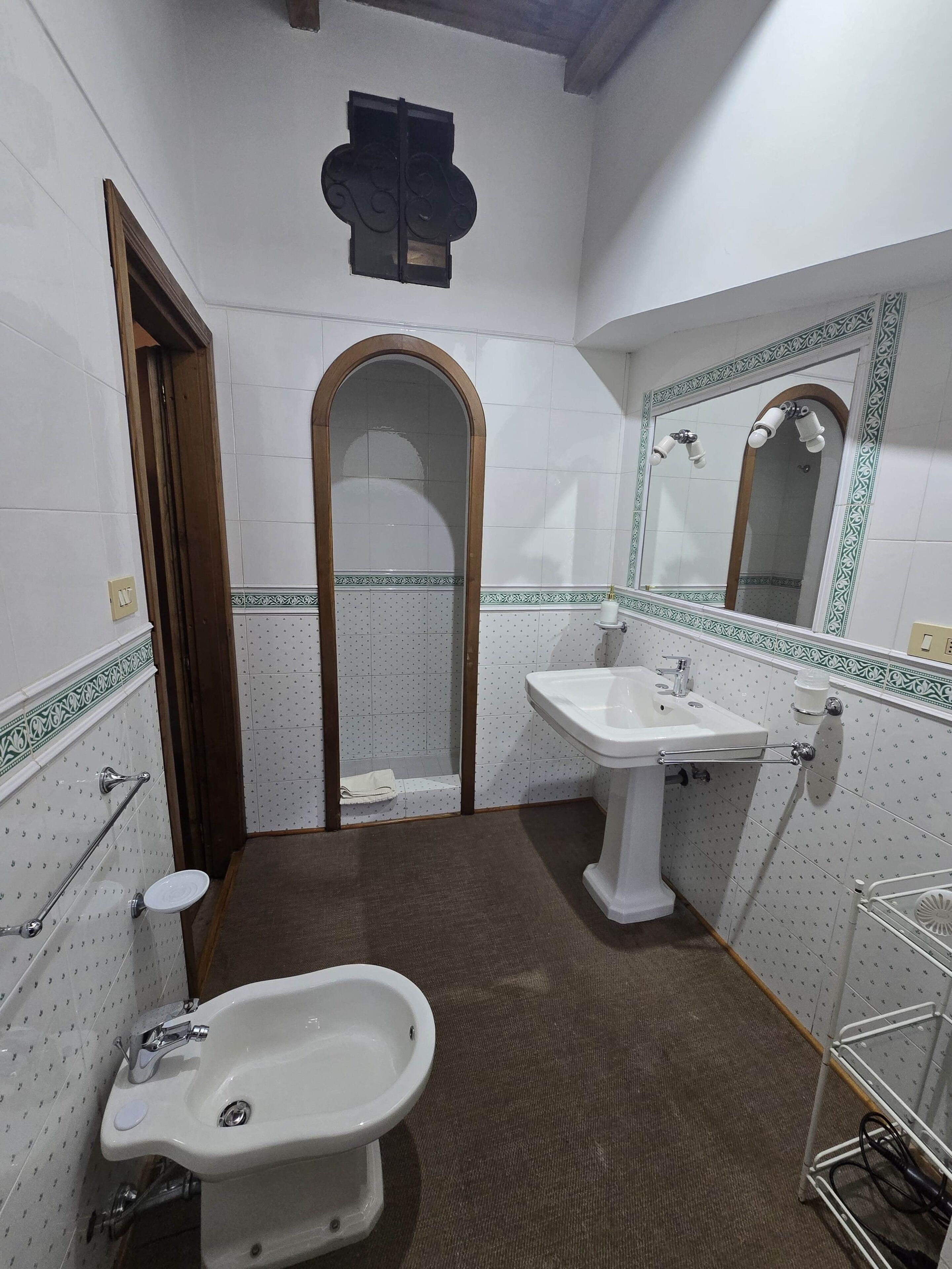 A bathroom with a toilet, bidet, sink, mirror, and towel rack.