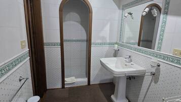 A bathroom with a toilet, bidet, sink, mirror, and towel rack.