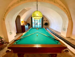 A pool table with a green felt surface, surrounded by a white wall with an arched doorway.
