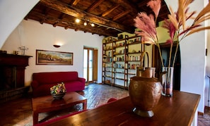 A cozy room with a red sofa, a wooden coffee table, a bookshelf, and a large vase with pampas grass.