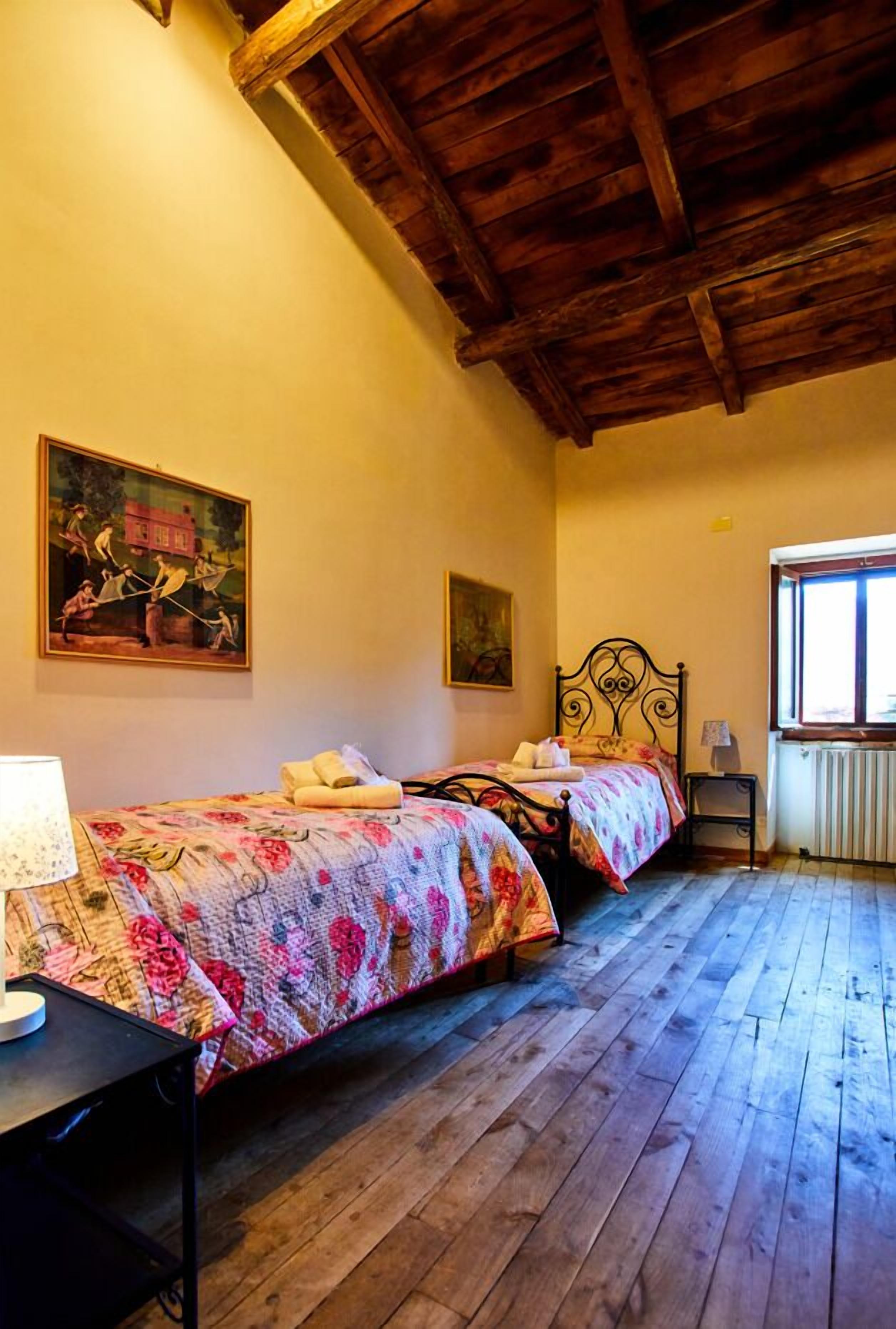Une chambre avec deux lits, un plancher en bois, une fenêtre avec vue et un radiateur.