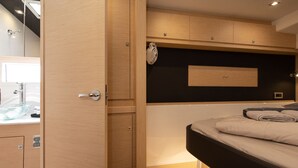 A modern bedroom with a wooden wardrobe, a bedside table, and a black headboard. - Sun-Kissed Sailing Adventure in Sibenik, Croatia (Primošten)