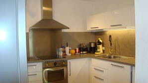 Uma cozinha moderna com eletrodomésticos de aço inoxidável, armários brancos e forno embutido.