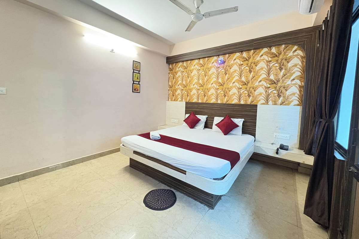 A hotel room with a bed, ceiling fan, air conditioning unit, and a decorative wall panel.