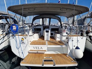 Um iate com deck coberto, o nome 'Vela' na lateral e o logotipo 'Novak Marine'.