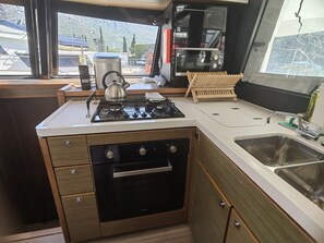 A compact kitchen with a gas stove, oven, and a sink. - Dubrovnik Delight: A Sun-Kissed Sailing Experience (Komolac)