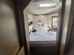 Ein kompakter, gut beleuchteter Raum mit einem Bett, einem kleinen Fenster und einem Oberlicht.