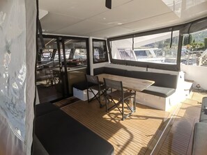 L'intérieur d'un bateau, avec un espace repas, des sièges et des fenêtres.