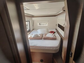 Ein kleines Schlafzimmer mit einem Einzelbett, einem kleinen Fenster und einer eingebauten Ablage.