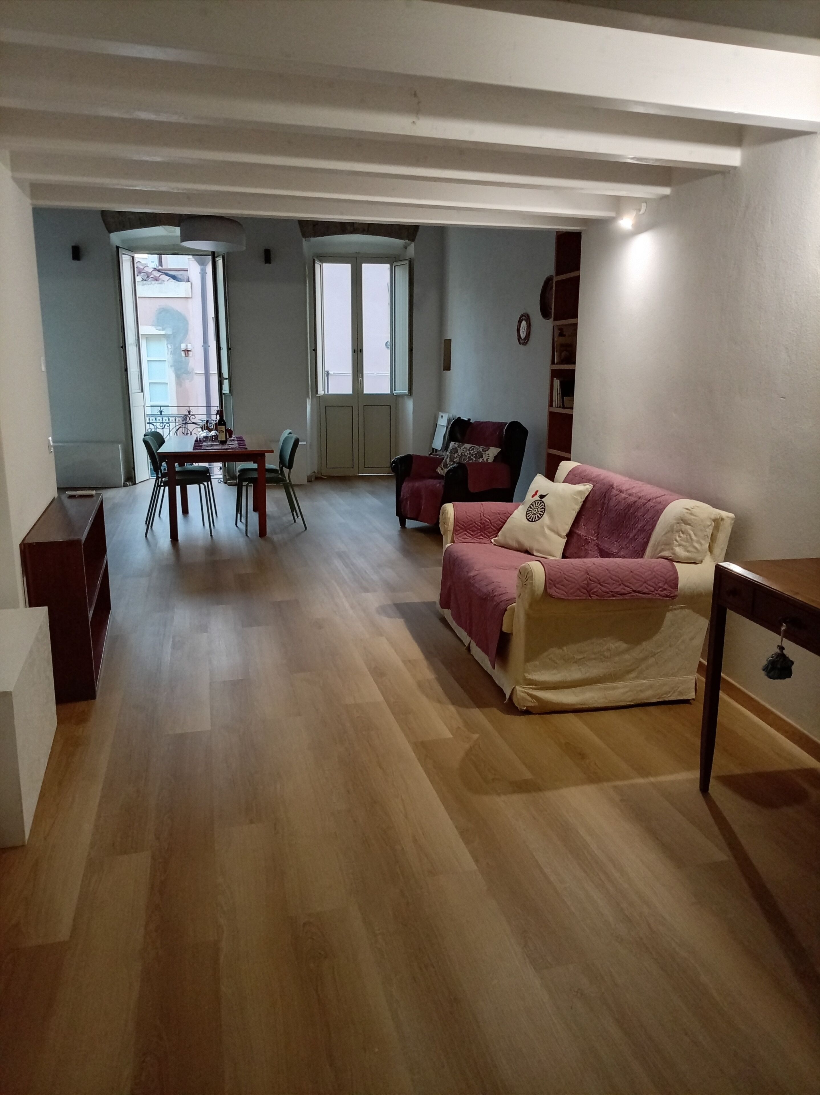 A living room with a sofa, a dining table with chairs, and a bookshelf.