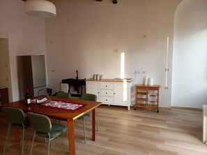 Eine moderne Küche mit Kühlschrank, Spüle und Holzschränken. Ein Esstisch mit Stühlen und einer Lampe darüber.