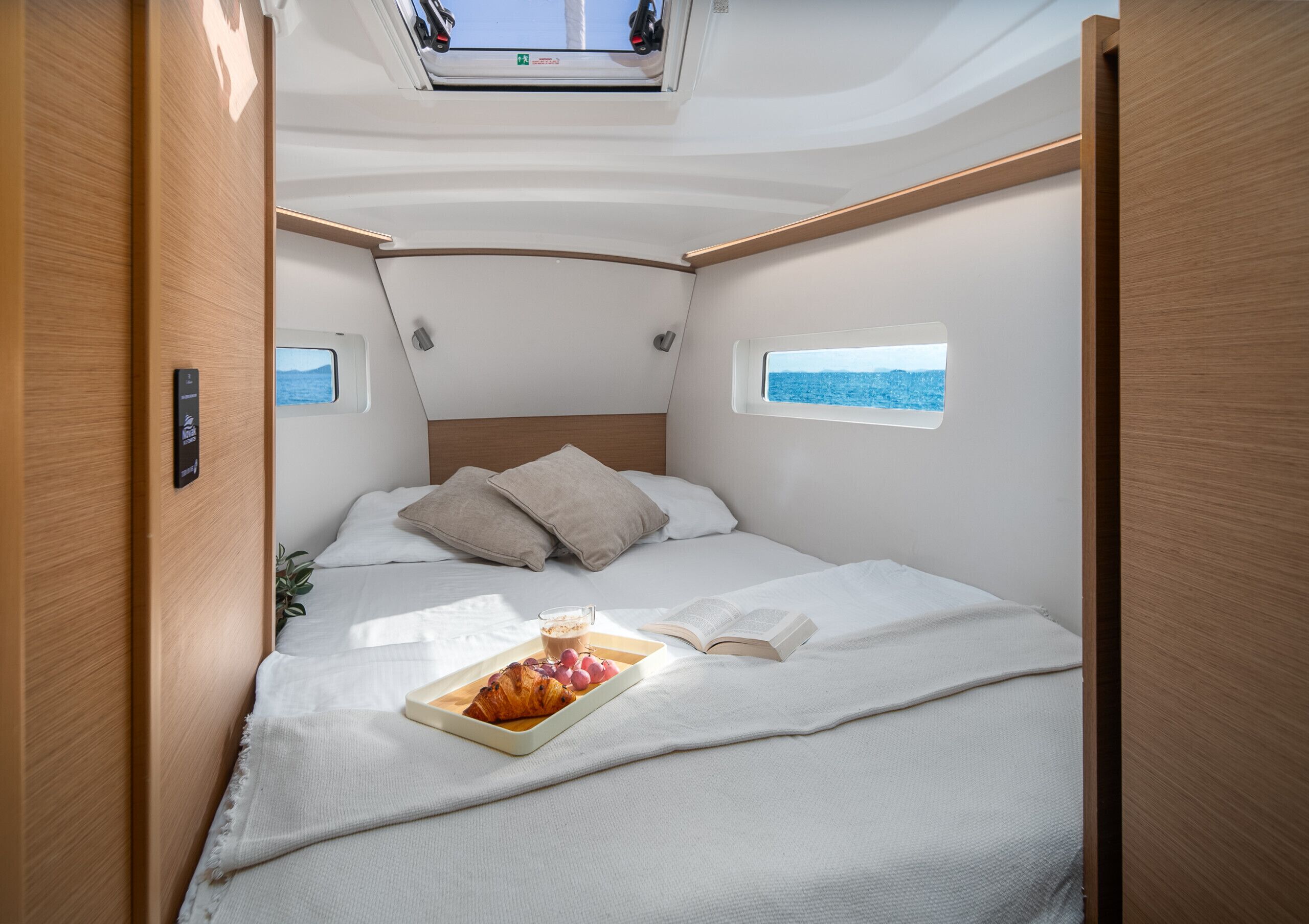 Een compact, goed verlicht interieur met een bed, een dienblad met eten en een boek, wat een gezellig, zelfstandig verblijf doet vermoeden.