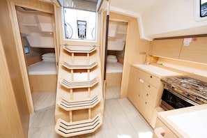 A compact RV interior with a bunk bed, a kitchenette, and a storage unit.