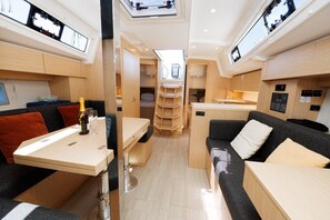 A compact RV interior with a dining area, a sofa, and a small kitchen.
