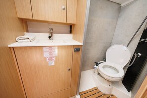 A compact bathroom with a sink, toilet, and shower.