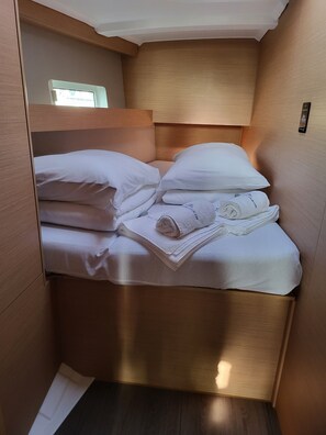 A compact, well-lit room with a bed, pillows, and neatly folded towels. - Sun-Kissed Sailing Adventure in Zadar, Croatia (Biograd na moru)