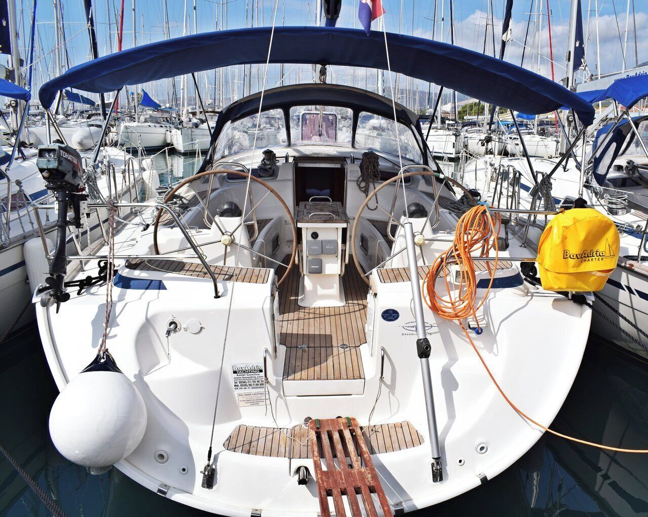 A sailboat with a cabin, a steering wheel, and a blue canopy.