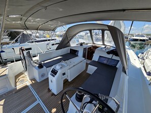 A yacht's deck with a seating area, steering wheel, and control panel.