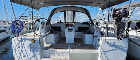 A sailboat docked at a marina with a covered deck, a Suzuki outboard motor, and the name 'LUNA' on the bow.