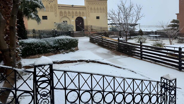 Un patio cubierto de nieve con un edificio tradicional que presenta arcos y diseños decorativos.