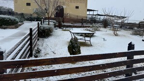 Un patio cubierto de nieve con una cerca de madera, bancos y un edificio de arquitectura tradicional.