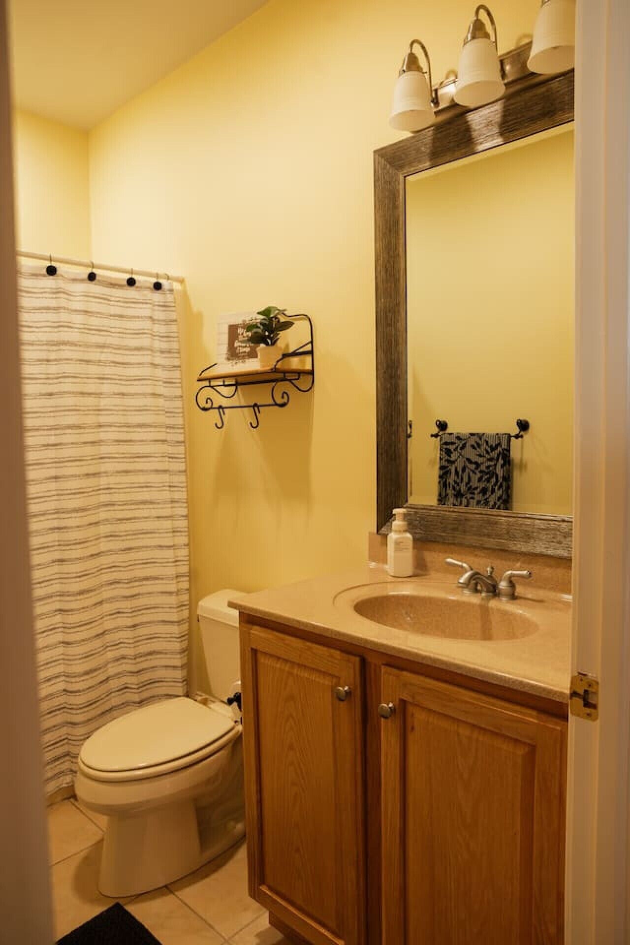 A bathroom with a toilet, a sink with a mirror, and a shower curtain.