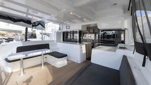 A boat's deck with a seating area, a small table, and a window. - Sun-Kissed Sailing Adventure in Split, Croatia (Split)