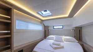 A modern hotel room with a skylight, a bed with white linens, a built-in shelf, and a small window. - Sun-Kissed Sailing Adventure in Split, Croatia (Split)
