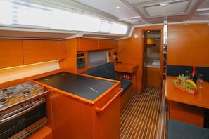 A compact galley with a stove, a small seating area, and a dining table with a fruit basket. - Sun-Kissed Sailing Adventure in Split, Croatia (Kaštel Gomilica)