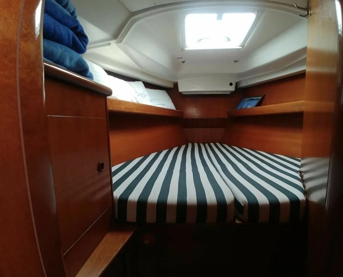 Une petite cabine équipée d’un lit superposé, d’un puits de lumière et d’une petite table avec un appareil.